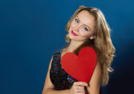 A girl holding a red color heart shaped paper